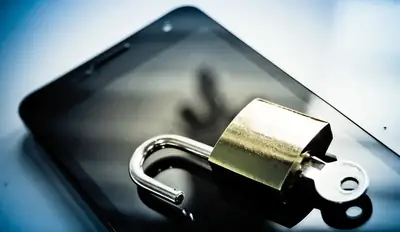 Brass padlock resting on a smartphone screen, symbolizing phone security